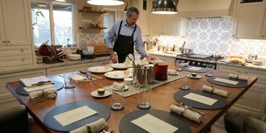 Man setting a formal dining table in a cozy kitchen.