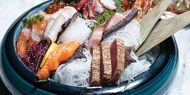 A bowl of assorted fresh sashimi with garnishes and shredded radish.