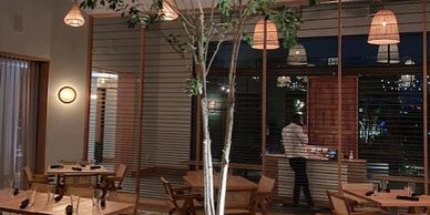 Cozy restaurant interior with wooden tables, chairs, and warm lighting.