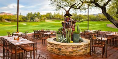Outdoor dining area overlooking a golf course with rustic decor.