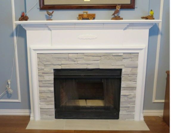 White stone fireplace with decorative items on the mantel.