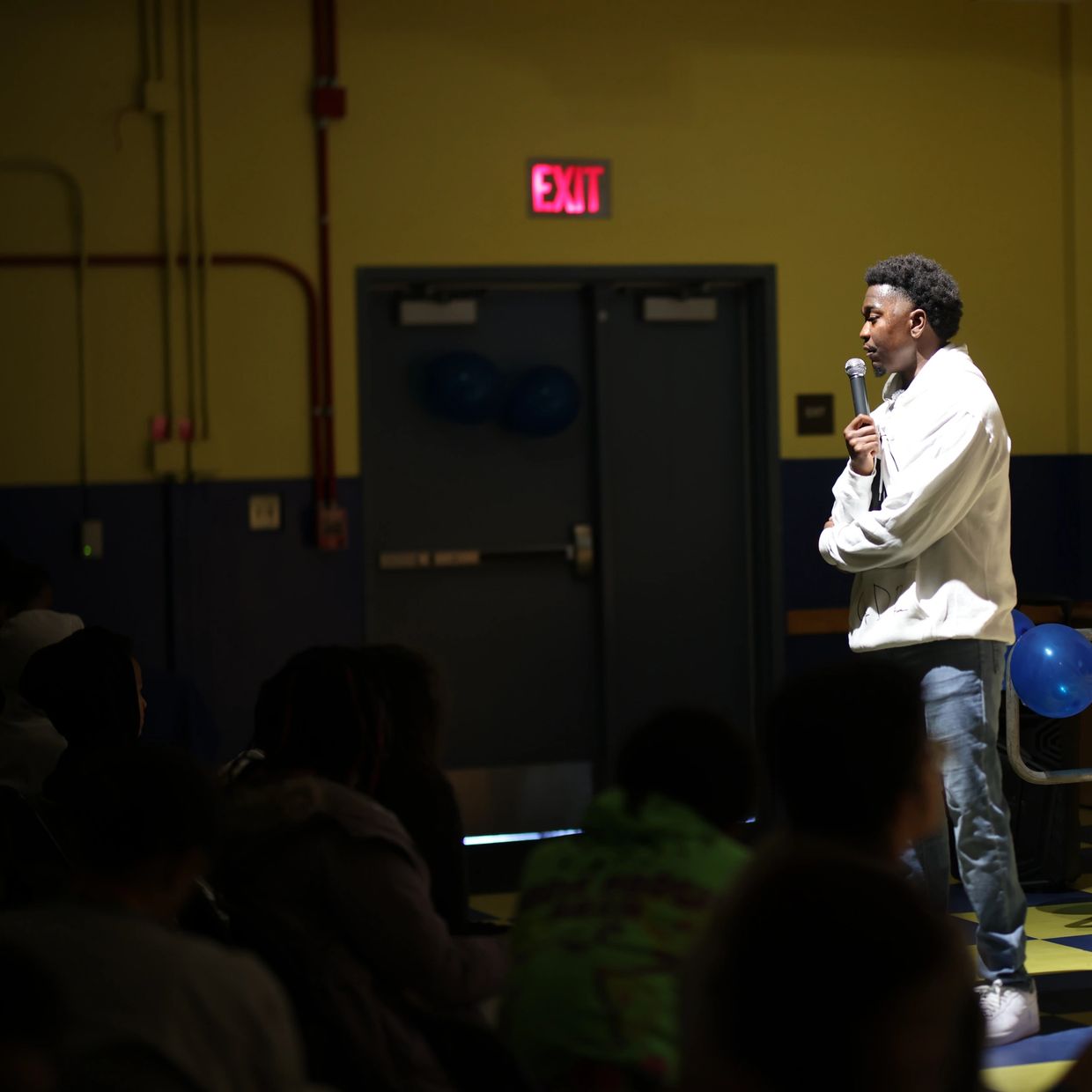 Man speaking with a microphone in front of an audience.