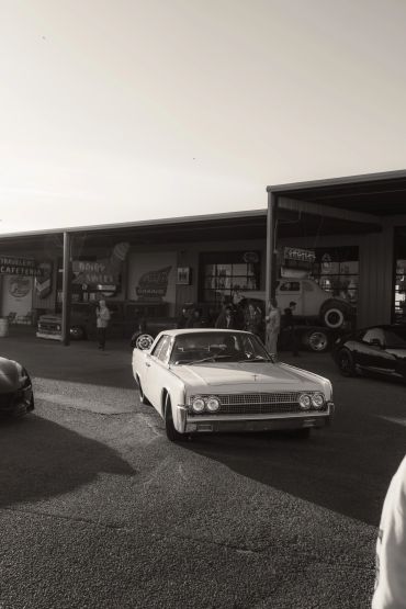 Vintage car parked in front of a retro garage during daytime.