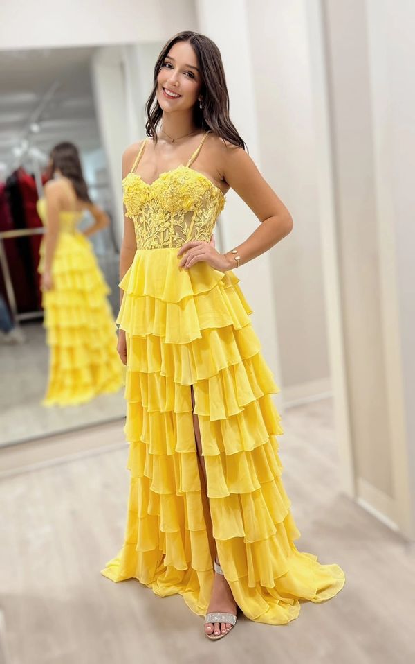 Woman in a bright yellow ruffled gown smiling indoors.