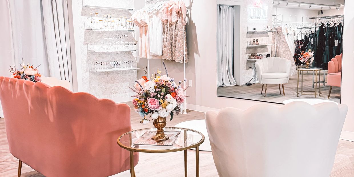 Elegant boutique seating area with pink and white chairs and floral decor.