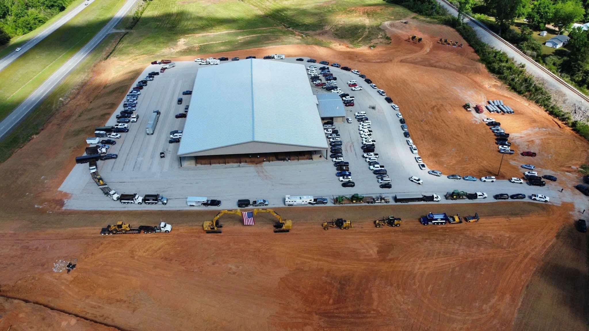 Aerial view of a large building with vehicles and machinery neatly arranged around it.