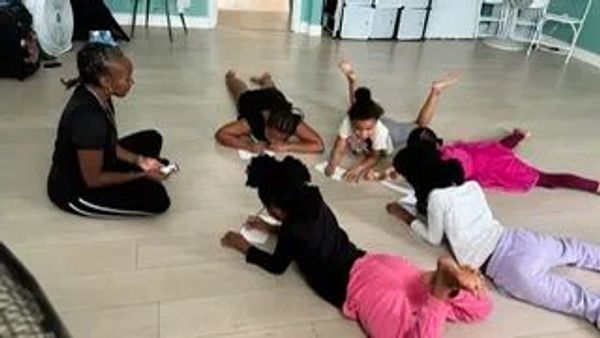 Children lying on the floor engaged in an activity with a woman supervising.