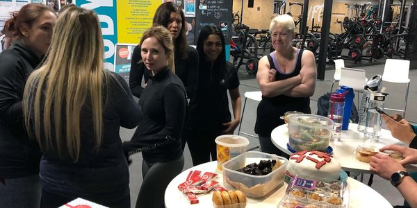 Group of gym members socializing and enjoying snacks post-workout, reflecting fun gym community.