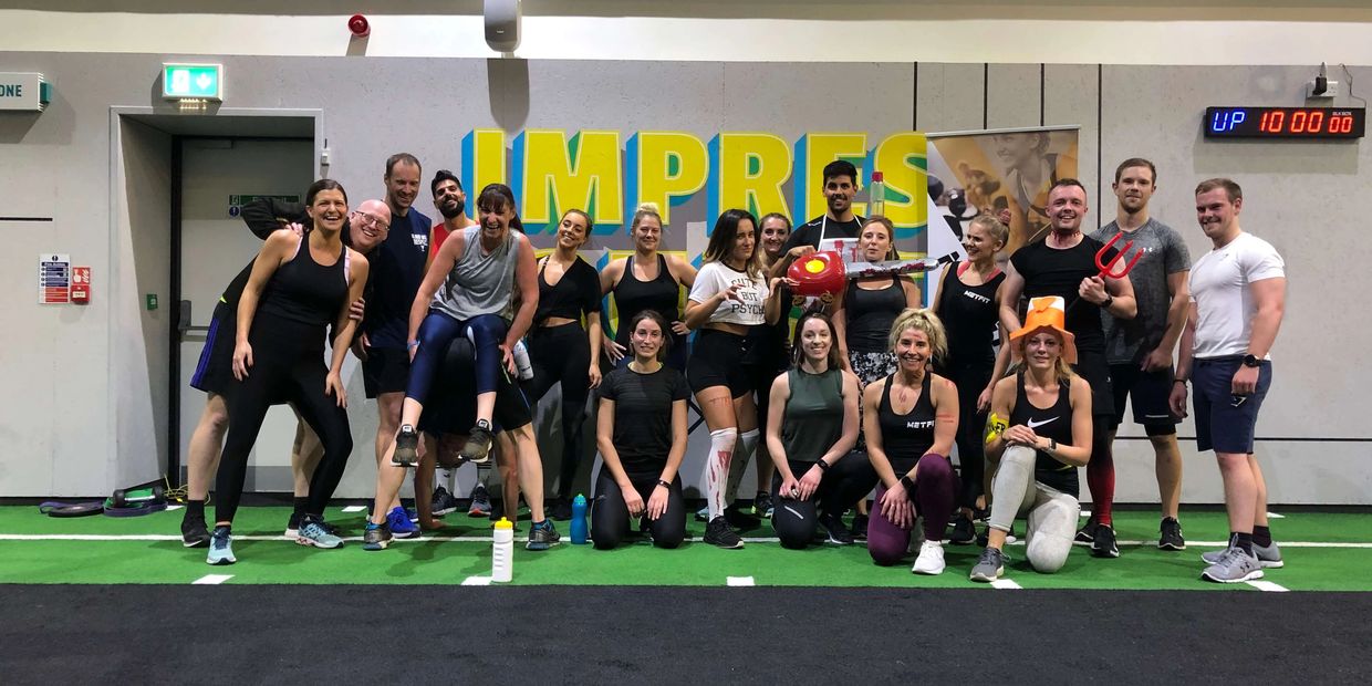 Group of smiling gym members and coach posing after workout at MetFit, showing community and fun.
