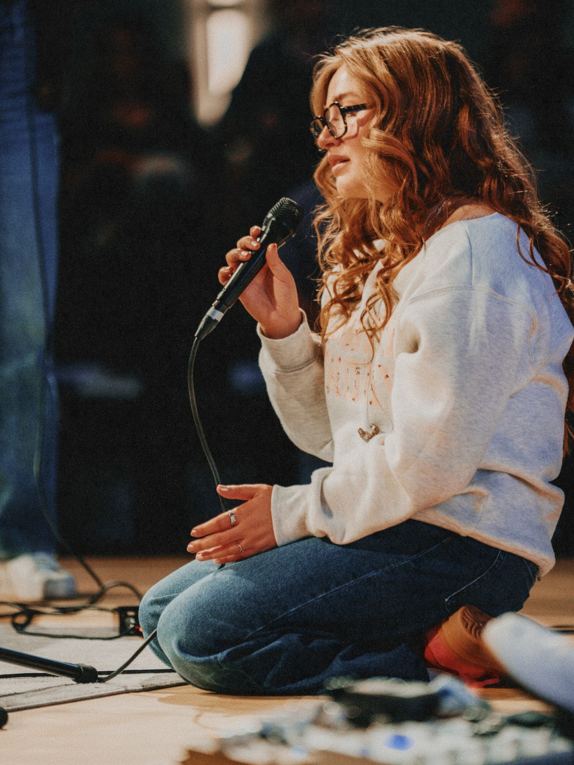 Young woman singing with microphone indoors.