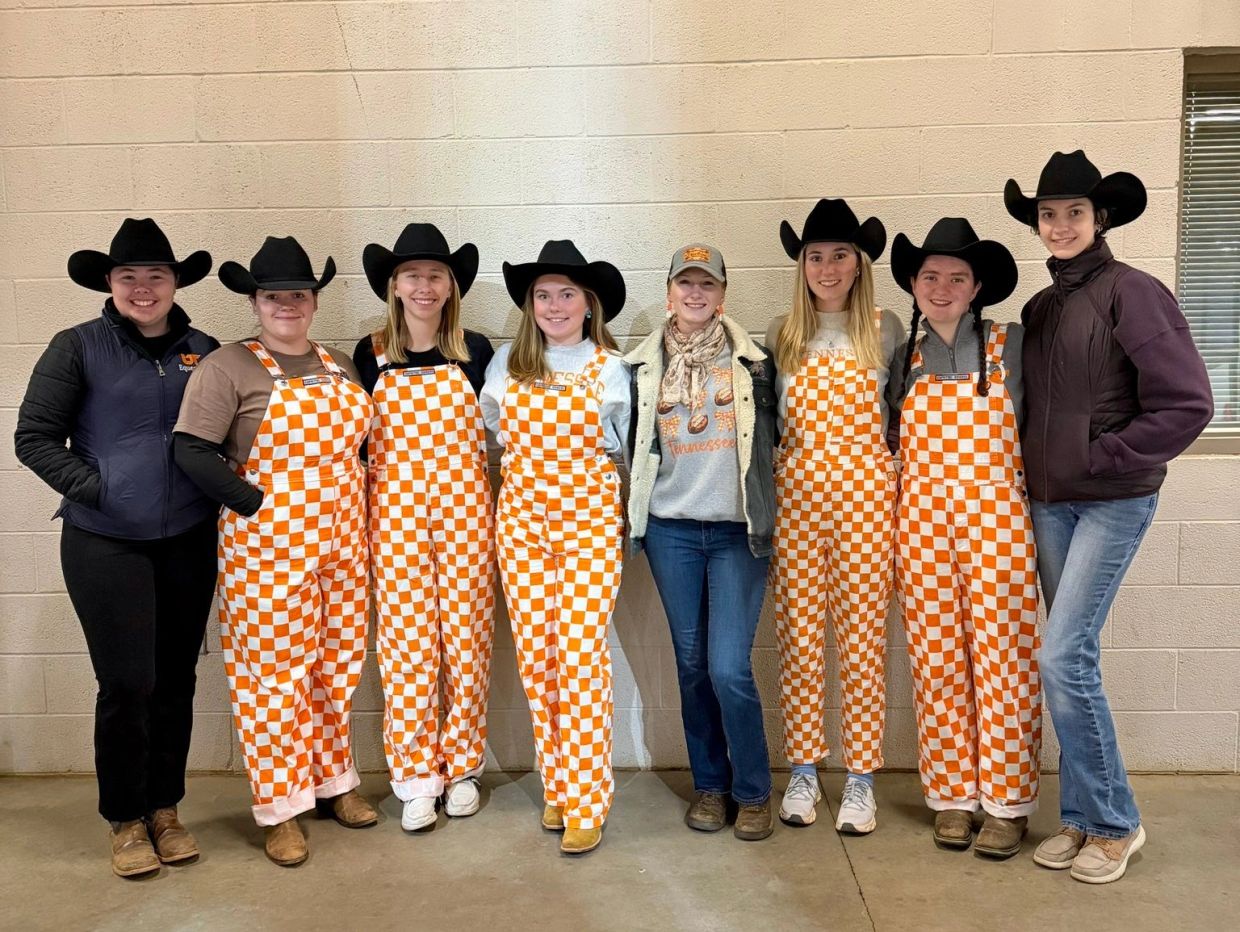 Group of young women in cowboy hats, some in orange checkered overalls.