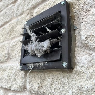 Close-up of a dusty ventilation vent on a textured wall.