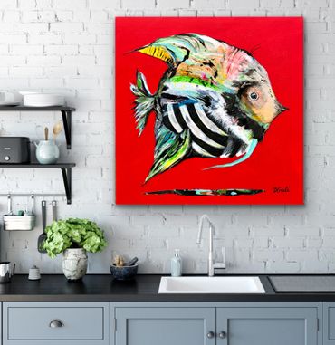 Colorful fish painting on a vibrant red canvas above a kitchen sink.