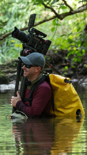 Rhett Cutrell walking through river in Togo jungle with Red Camera.  Fornever Productions