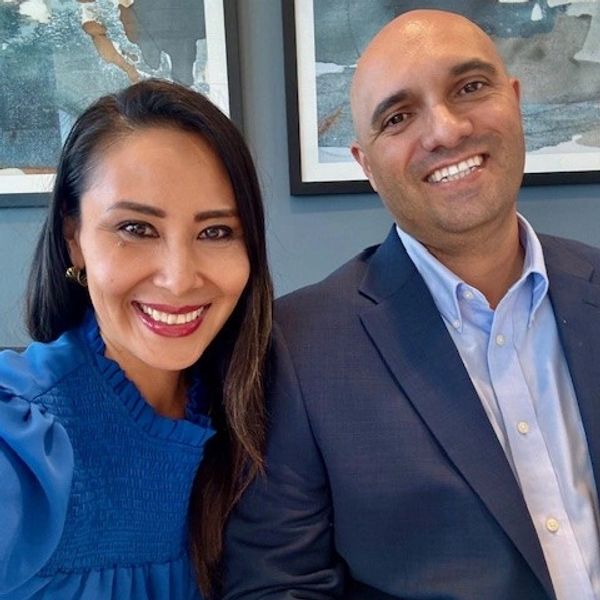 Smiling man and woman posing together indoors in formal attire.