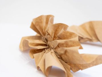 Crumpled brown paper twisted into a spiral shape on a white surface.