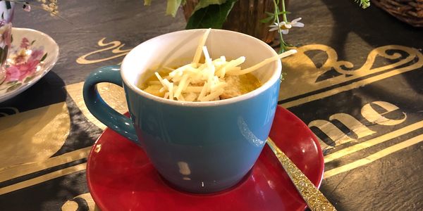 Cup of soup with freshly grated parmesan cheese.
