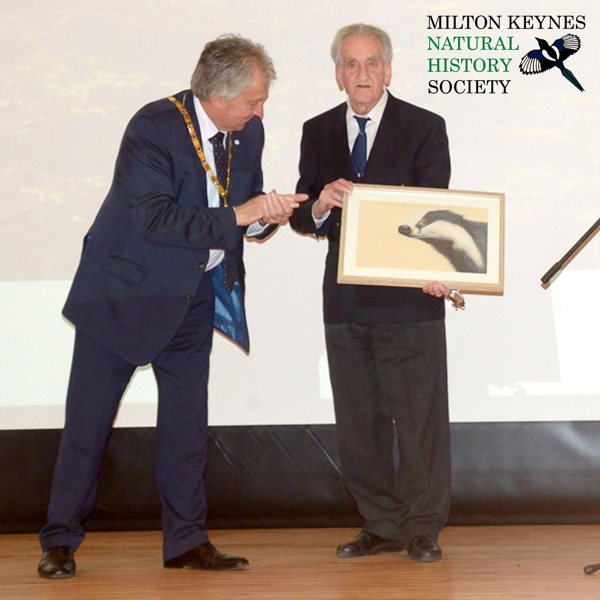 Two men in suits with a framed badger picture, Milton Keynes Natural History Society.