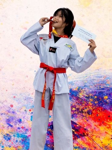 Young martial artist celebrates with a medal and certificate in a colorful setting.