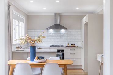 Modern kitchen with white cabinets and wooden dining table.