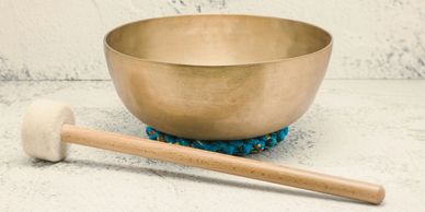 A Tiebetian singing bowl with a slim mallet next to itA Tibetan singing bowl accompanied by a slender mallet placed beside it.
