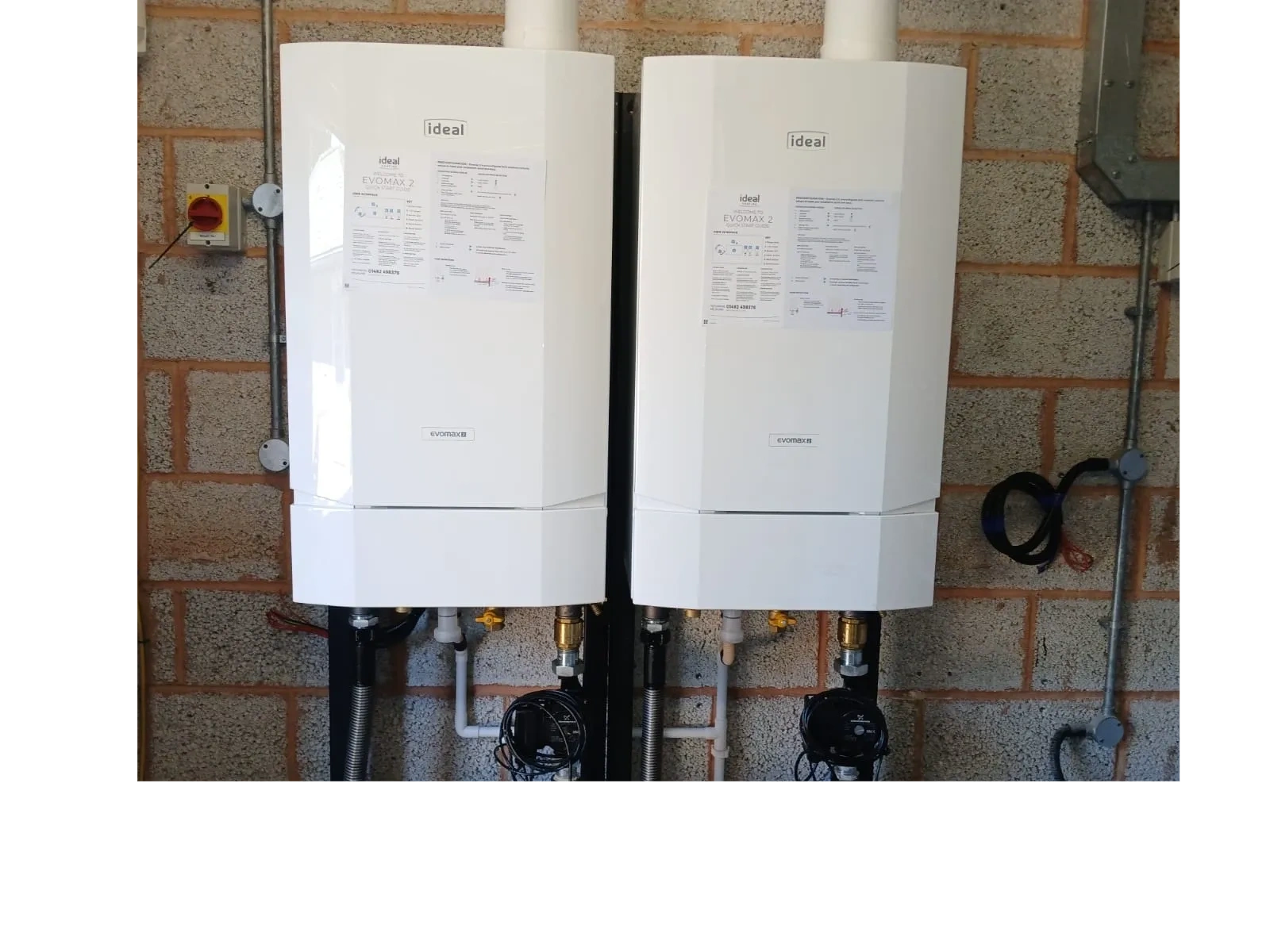 Two white Ideal Evomax 2 boilers mounted on a brick wall.