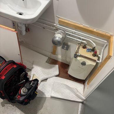 Utility room corner with pipes and tools on the floor.