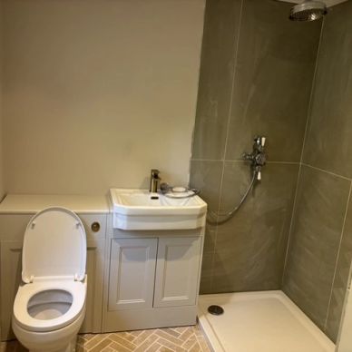 Compact bathroom with toilet, sink, and shower area.