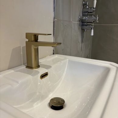 Modern sink with gold faucet and drain stopper.