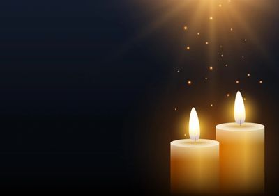 Two glowing candles with warm light against a dark background.