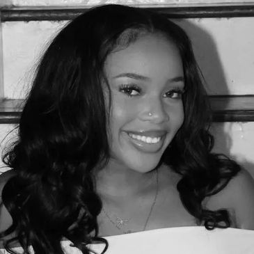 Smiling young woman with long curly hair in black and white photo.