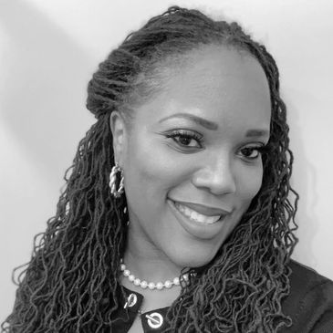 Smiling woman with braided hair and pearl necklace.