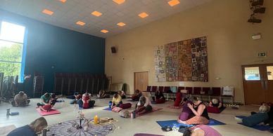 Group yoga session in a spacious room with sunlight.