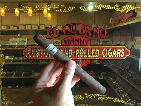 manny holding a cigar in front of window of humidor in league city