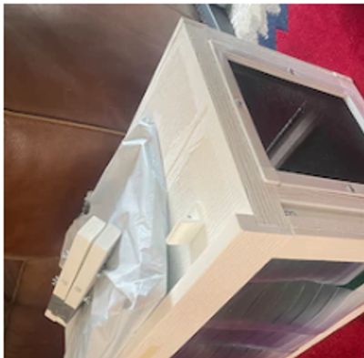 A cardboard box wrapped in plastic on a couch.