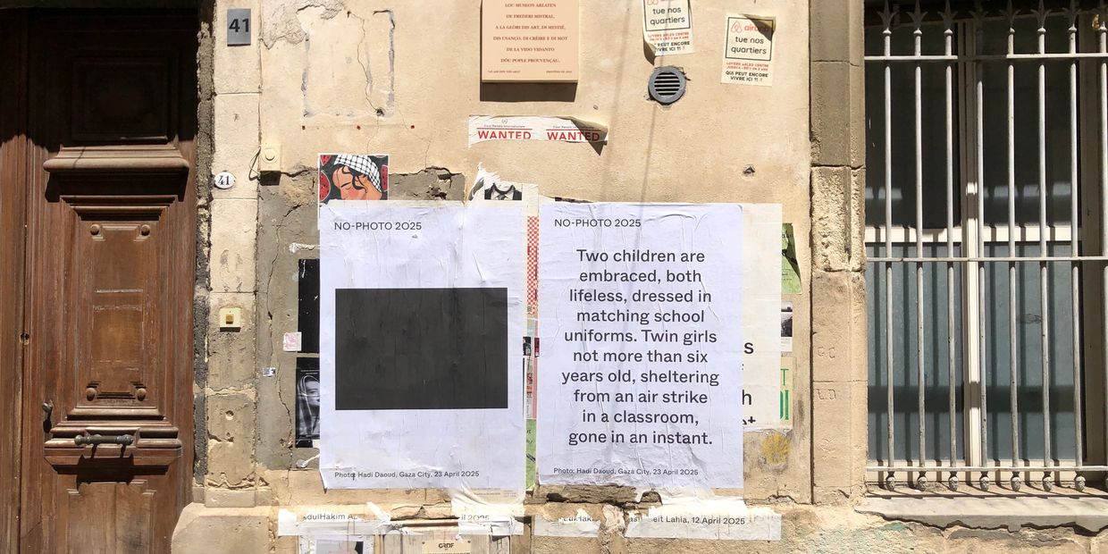 Wall posters memorialize twin girls lost in an air strike, with a blacked-out photo and descriptive text.