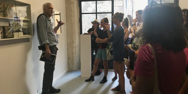 A man giving a talk to a group in an art gallery.