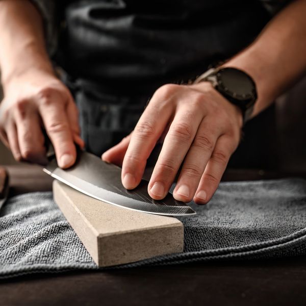 Hands sharpening a blade on a whetstone symbolizing precision, mastery, and alignment.