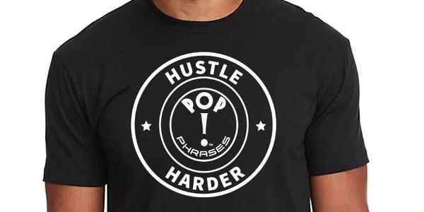 Black t-shirt with a white circular design and the words 'Hustle Harder' and 'Pop Phrases'.