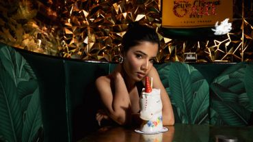 Woman sitting in a stylish bar with a colorful drink in a unicorn cup.
