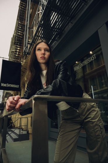 Young woman leaning on a railing outside a Wine Enthusiast store.