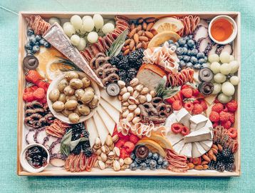A colorful charcuterie board with fruits, nuts, cheeses, and meats.