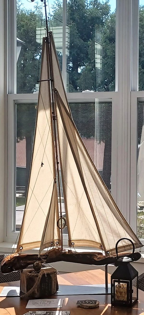 Voilier fait main, gros plan coque bois, voiles en tissu, sculpture navale.