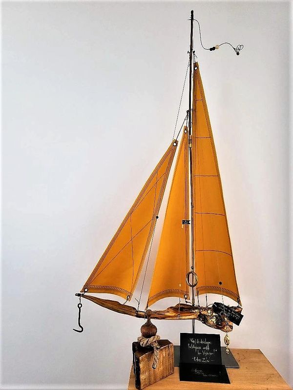 Voilier en bois sculpté, détails fins du mât et de la coque sous un ciel bleu.