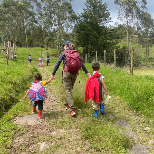 Persona y niños caminando en un sendero verde.