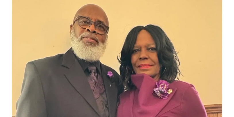 A dignified couple dressed in formal attire posing together indoors.