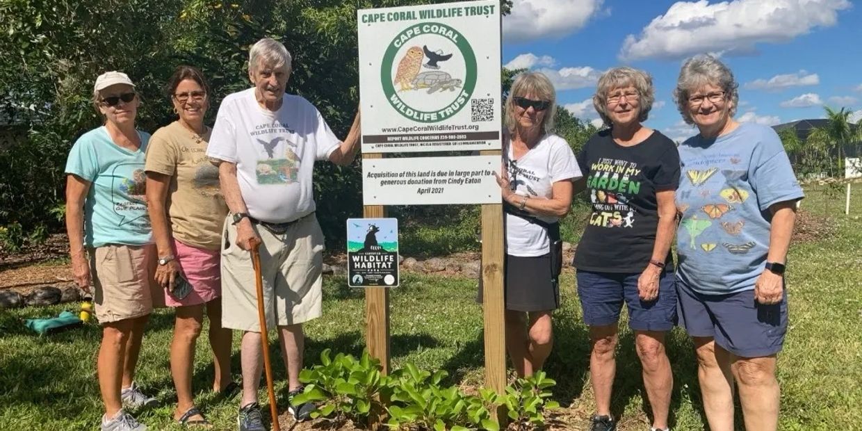 Group of six people standing next to a Cape Coral Wildlife Trust sign.