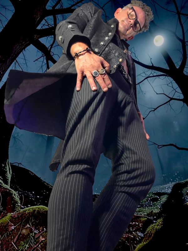 Man with rings in stylish dark outfit under moonlit sky.