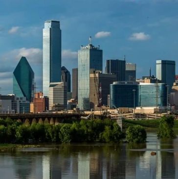 Dallas skyline with iconic buildings under a partly cloudy sky.