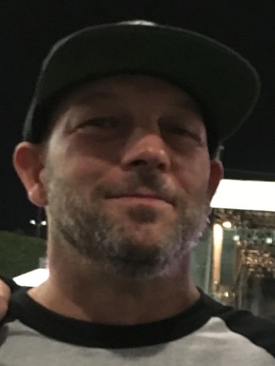 Close-up of a man wearing a cap at night.